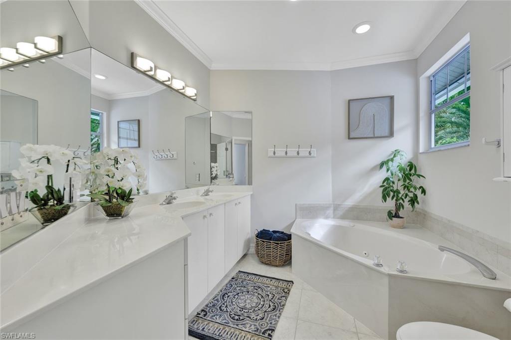 Bathroom featuring a tub, vanity, ornamental molding, and tile patterned flooring