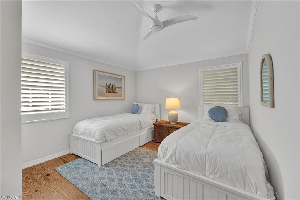 Bedroom with ceiling fan, wood-type flooring, and crown molding