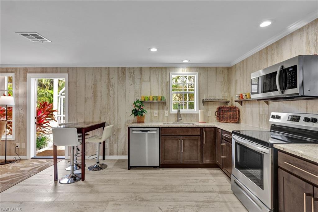 Kitchen with a healthy amount of sunlight, sink, crown molding, and stainless steel appliances