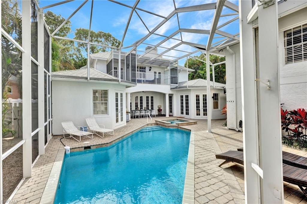 View of swimming pool featuring an in ground hot tub, a lanai, french doors, and a patio