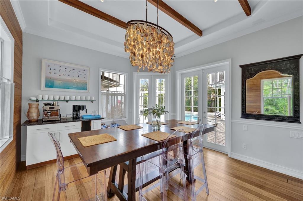 Dining space with beam ceiling, an inviting chandelier, light hardwood / wood-style flooring, ornamental molding, and french doors