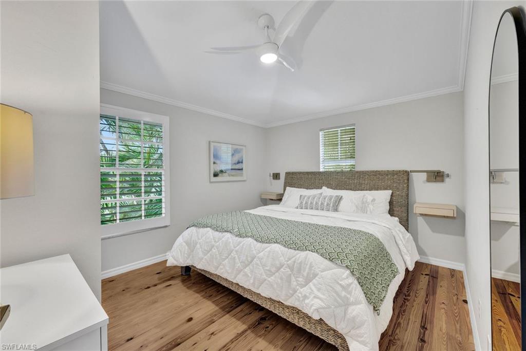 Bedroom with ceiling fan, ornamental molding, and light hardwood / wood-style flooring