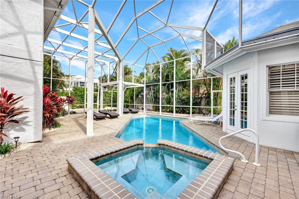 View of swimming pool featuring an in ground hot tub, glass enclosure, french doors, and a patio