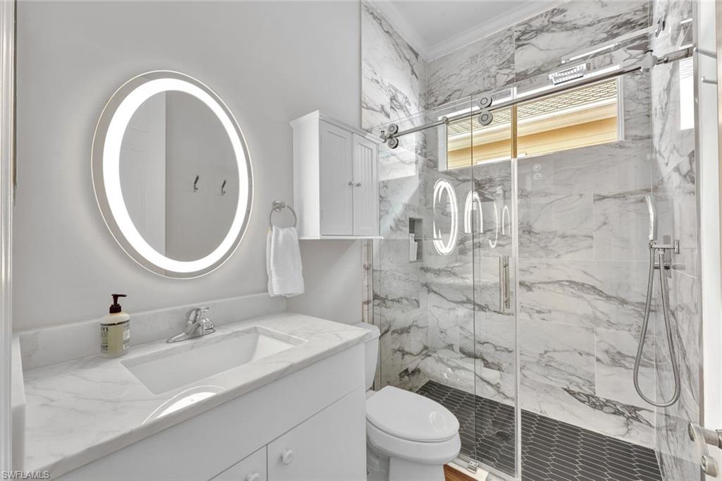 Bathroom with toilet, vanity, and a shower with door
