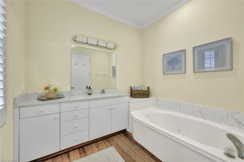Bathroom with hardwood / wood-style flooring, a bathtub, vanity, and crown molding