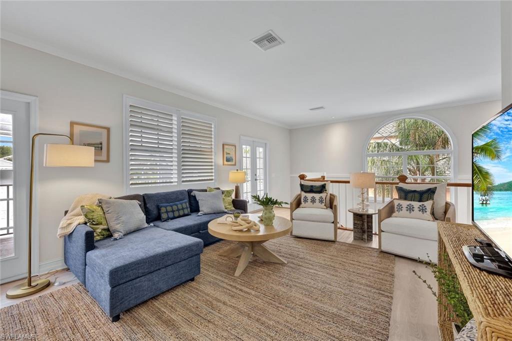 Living room with wood-type flooring, plenty of natural light, and ornamental molding