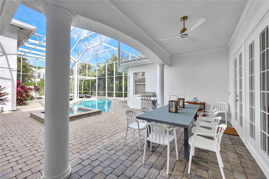 View of patio with glass enclosure, ceiling fan, and grilling area
