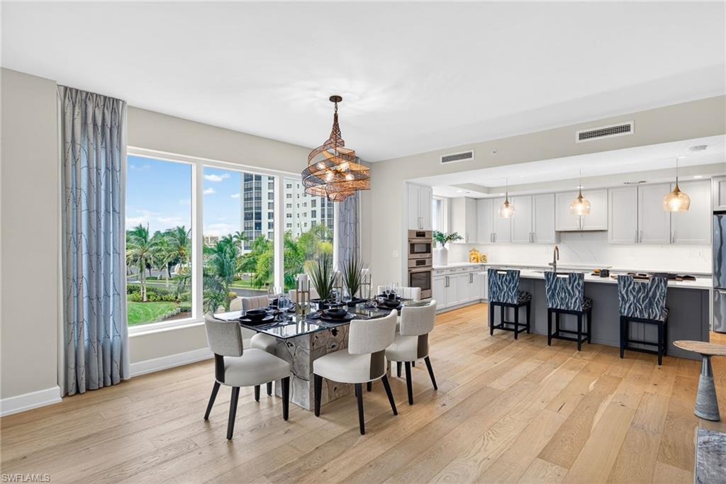 Dining area features large windows making a light and airy space , beautiful chandelier and wood finished floors