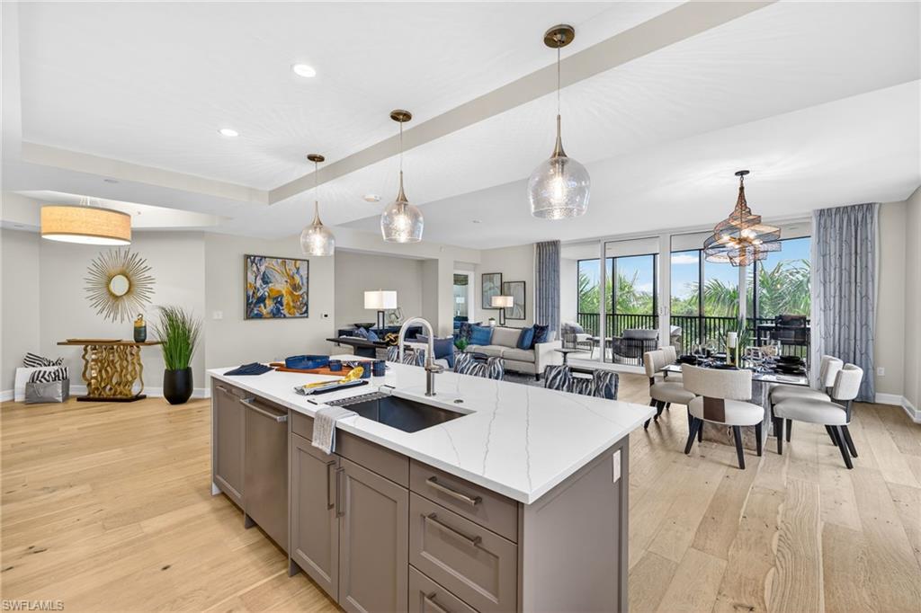 Large open space, kitchen with gray cabinetry, pendant lighting, and light stone counters, the open floor plan has nice flow through the dining and living room area