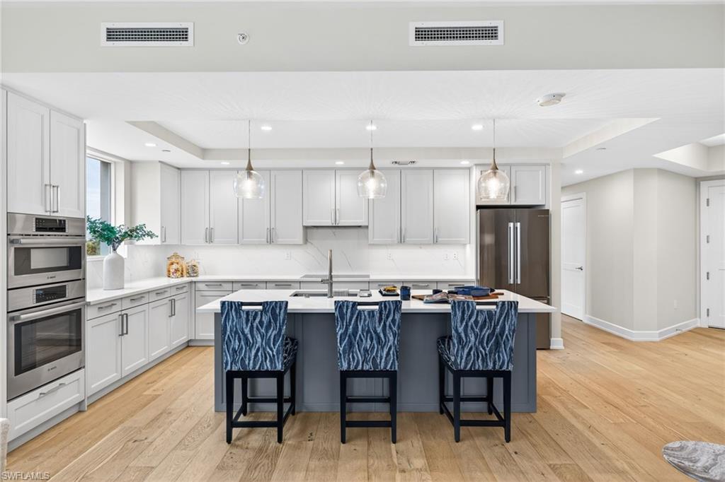Spacious Kitchen featuring hanging light fixtures, a tray ceiling, a breakfast bar area, stainless steel appliances, and recessed lighting