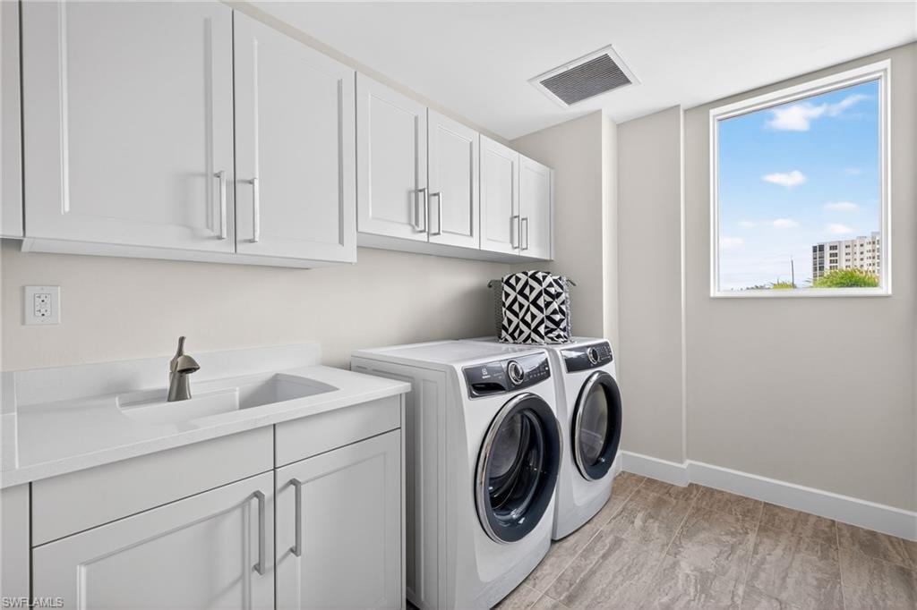 Spacious laundry room area with full size washer and clothes dryer and plenty of cabinet space