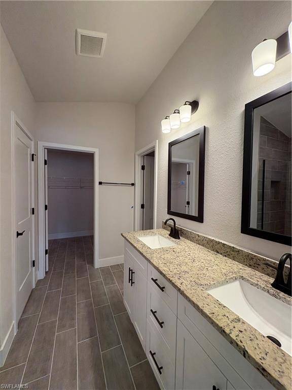 Full bathroom with double vanity and a spacious closet