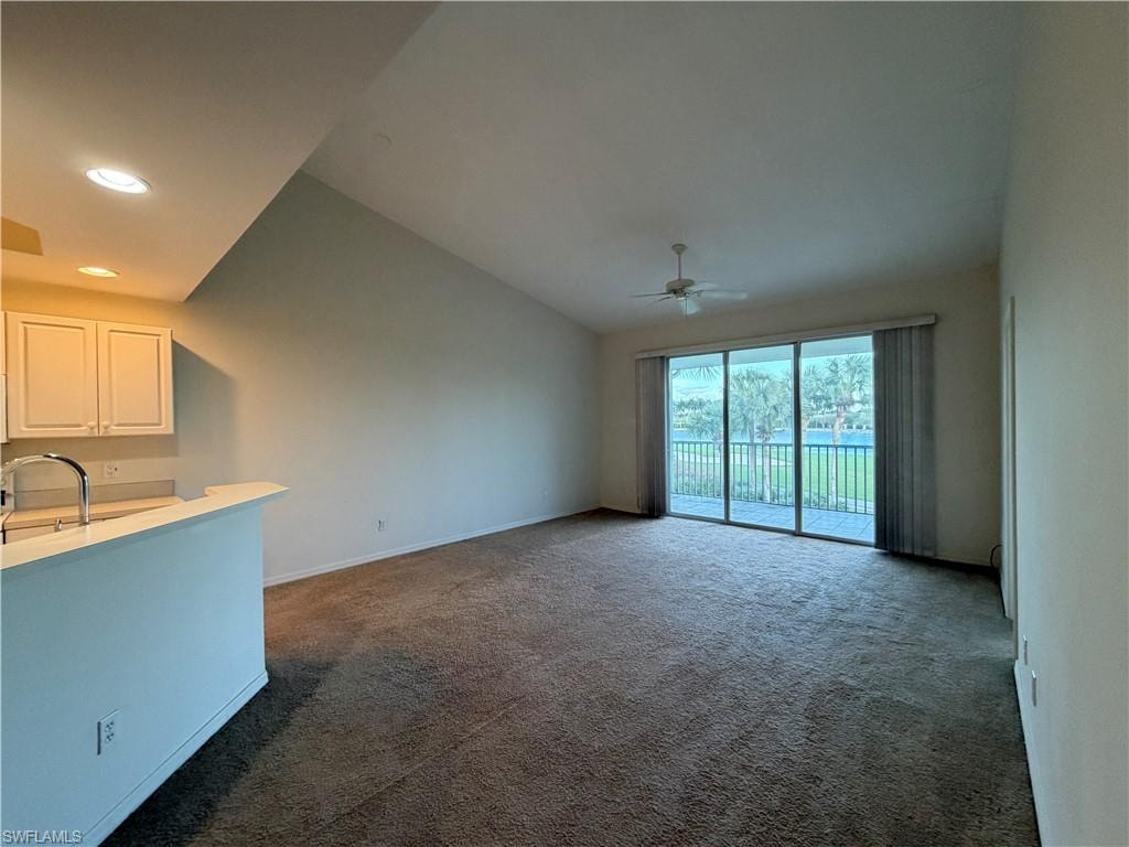 Unfurnished living room featuring dark carpet, vaulted ceiling, recessed lighting, and a ceiling fan