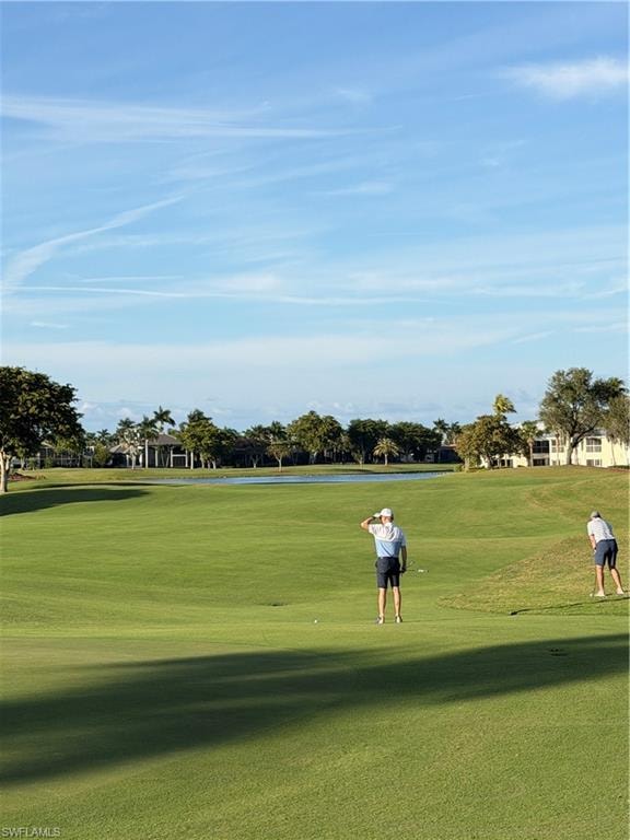 View of home's community with view of golf course and a yard