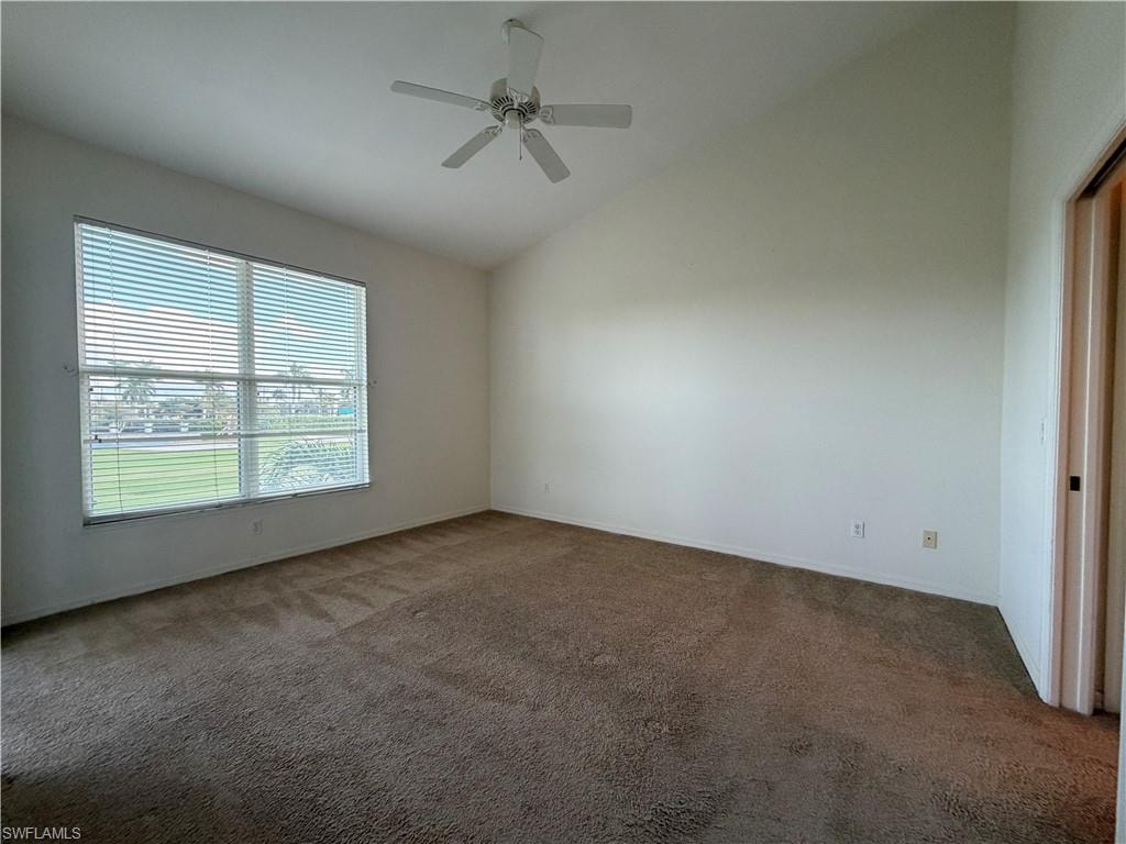 Carpeted spare room with ceiling fan and high vaulted ceiling