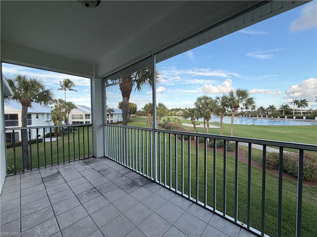 Balcony with a water view, view of golf course, and a sunroom