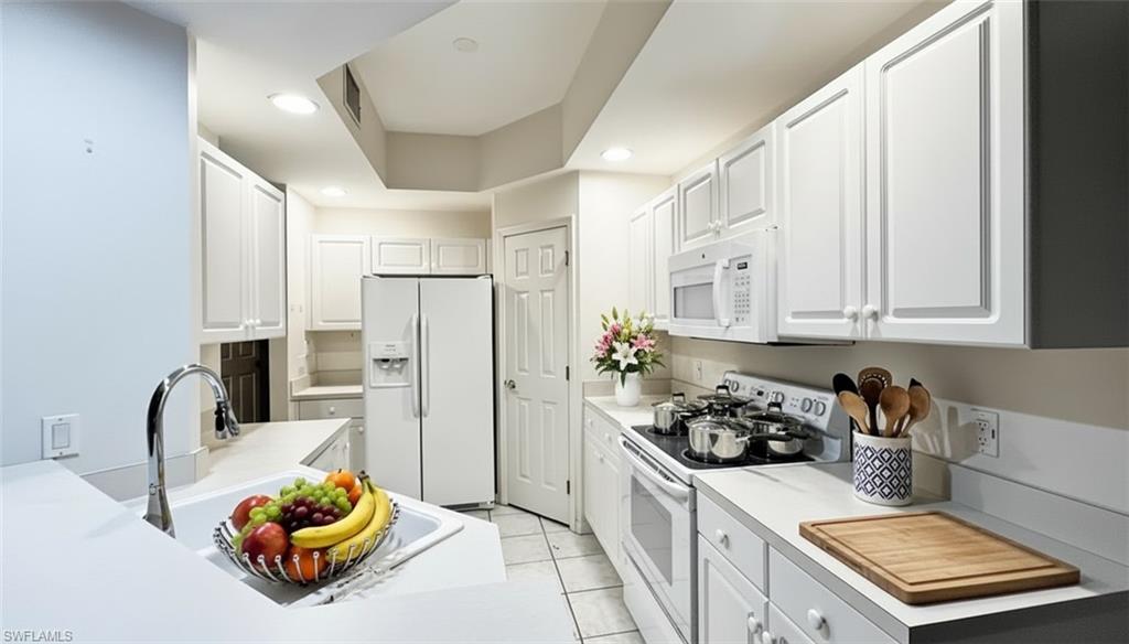 Kitchen with white appliances, white cabinetry, light countertops, recessed lighting, and light tile patterned floors
