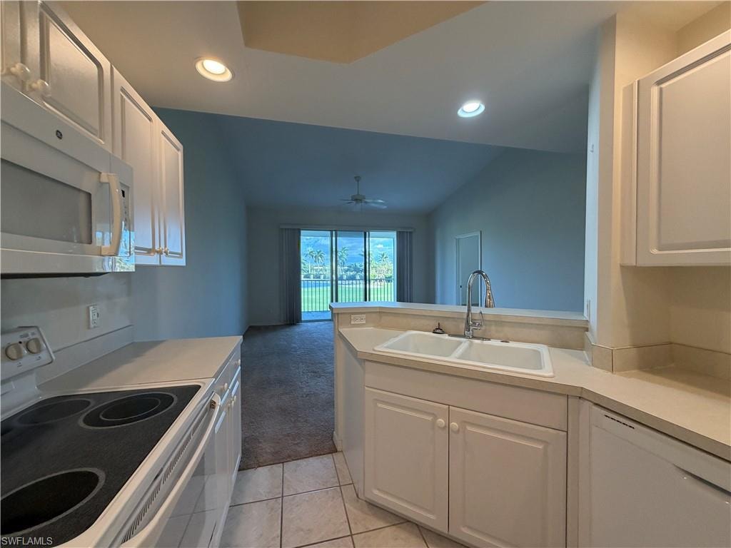 Kitchen featuring white appliances, light countertops, light colored carpet, white cabinets, and recessed lighting