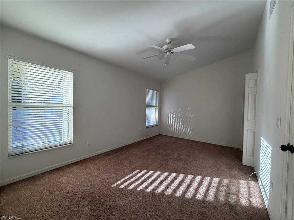 Carpeted empty room featuring vaulted ceiling and ceiling fan
