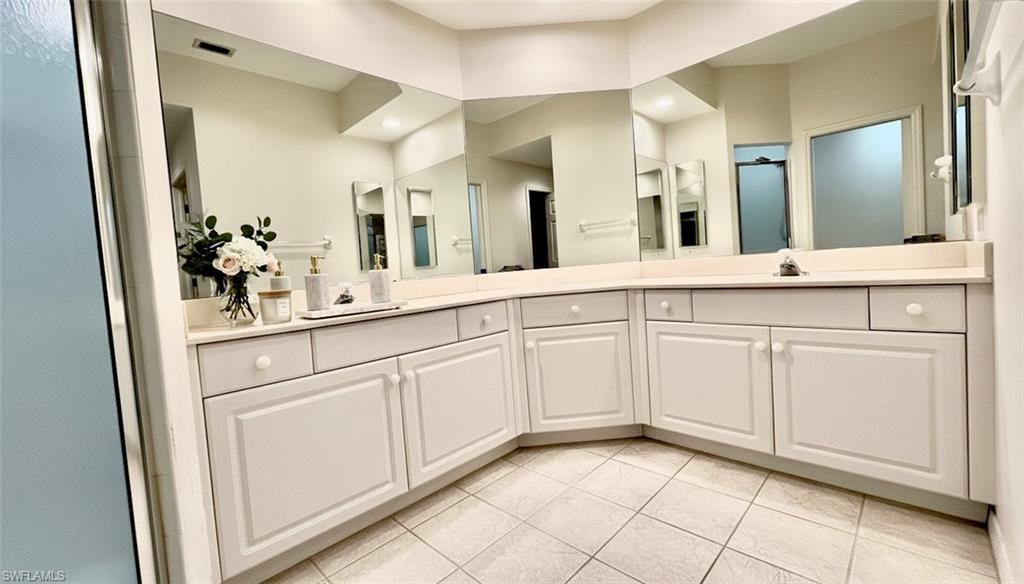 Full bath with double vanity and light tile patterned floors