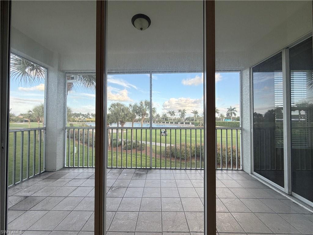 Unfurnished sunroom with tile patterned floors and a water view