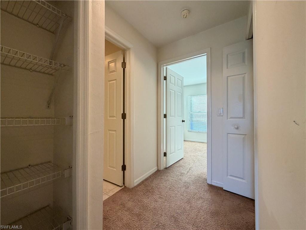Corridor with light colored carpet and baseboards