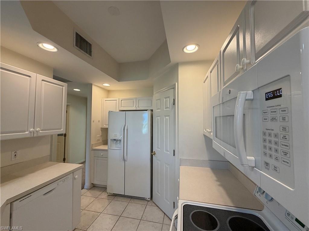 Kitchen with white appliances, light countertops, light tile patterned floors, recessed lighting, and white cabinets