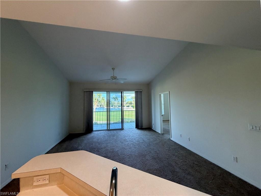Carpeted spare room with baseboards and high vaulted ceiling