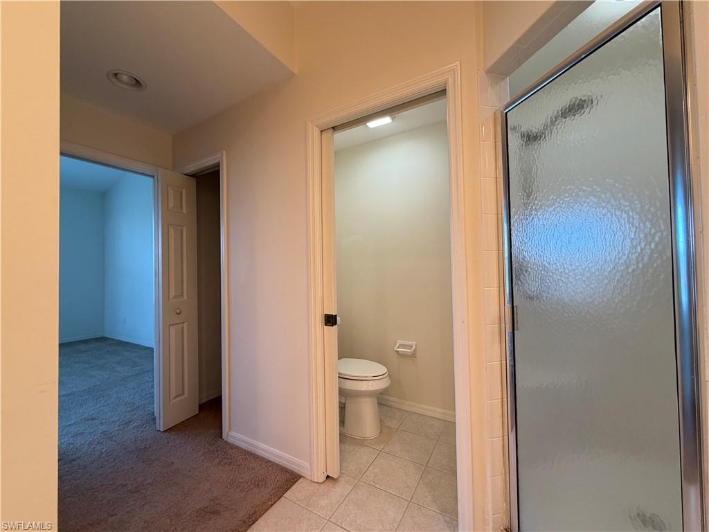 Full bath with light colored carpet, a stall shower, and light tile patterned floors