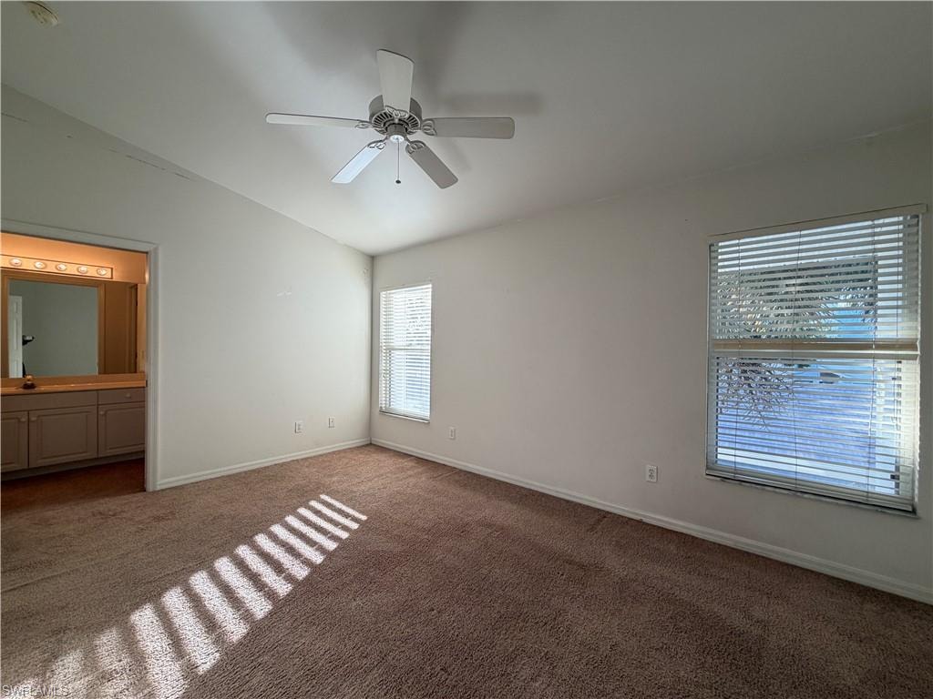 Unfurnished bedroom featuring lofted ceiling, carpet, a ceiling fan, and connected bathroom