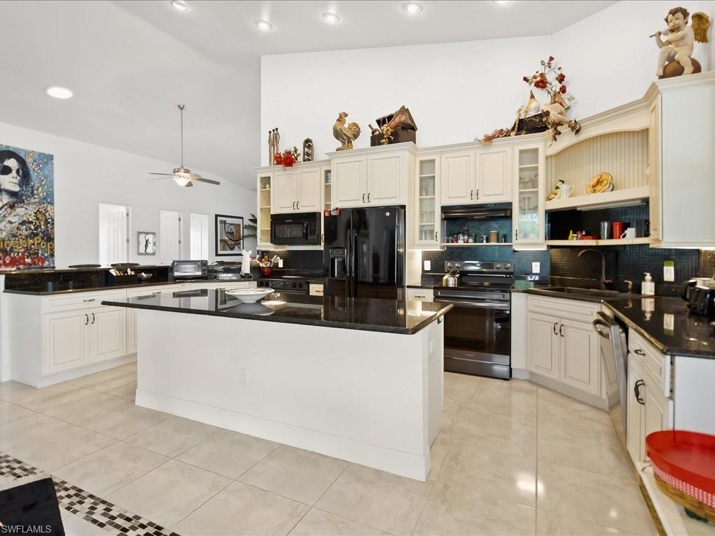Kitchen featuring open shelves, black appliances, dark stone counters, a peninsula, and recessed lighting