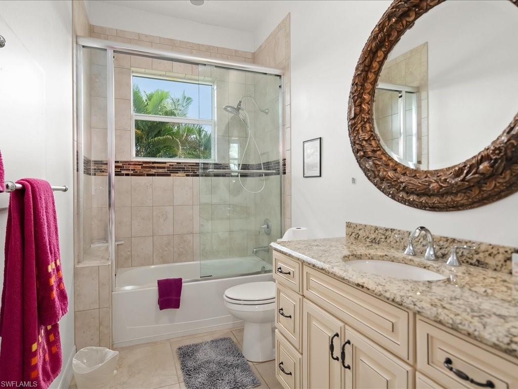 Full bathroom with vanity, bath / shower combo with glass door, and light tile patterned floors