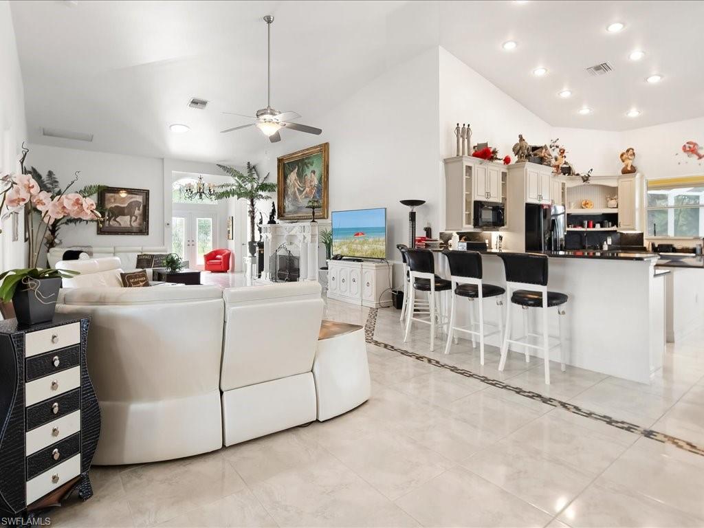 Living area featuring vaulted ceiling, plenty of natural light, a ceiling fan, recessed lighting, and a fireplace