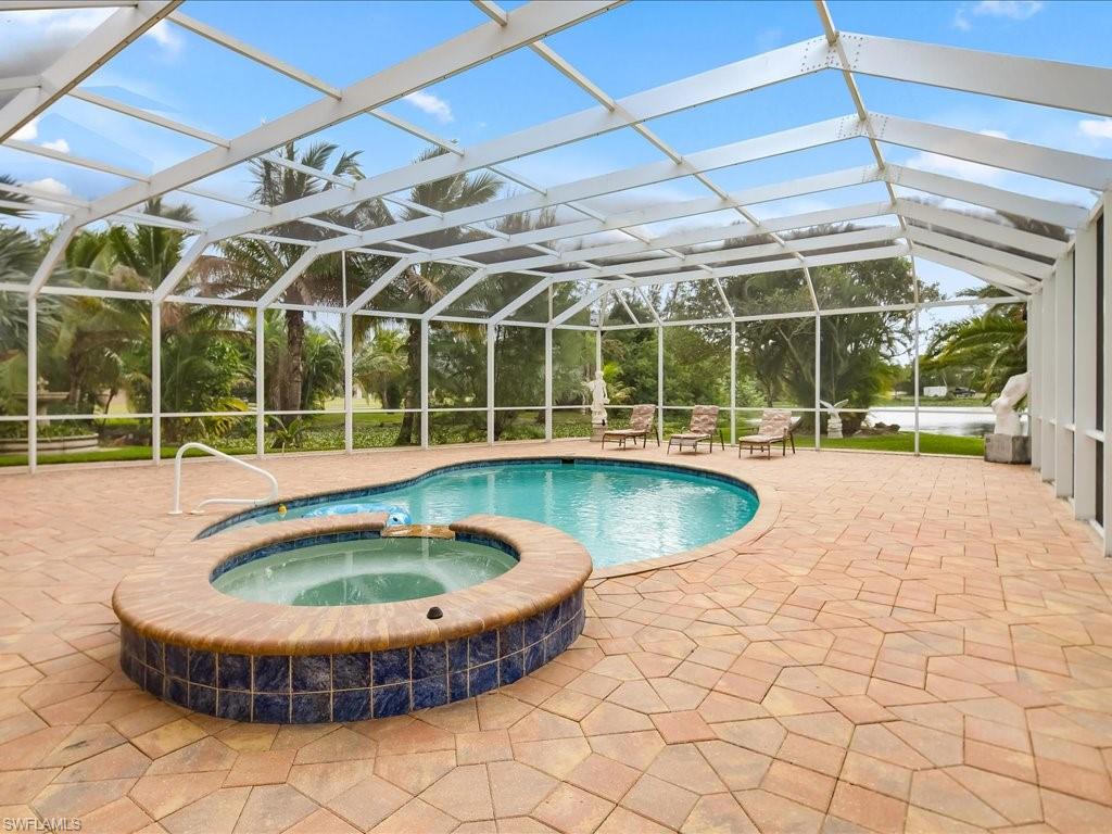 View of pool with a pool with connected hot tub, a patio, a sunroom, and a lanai