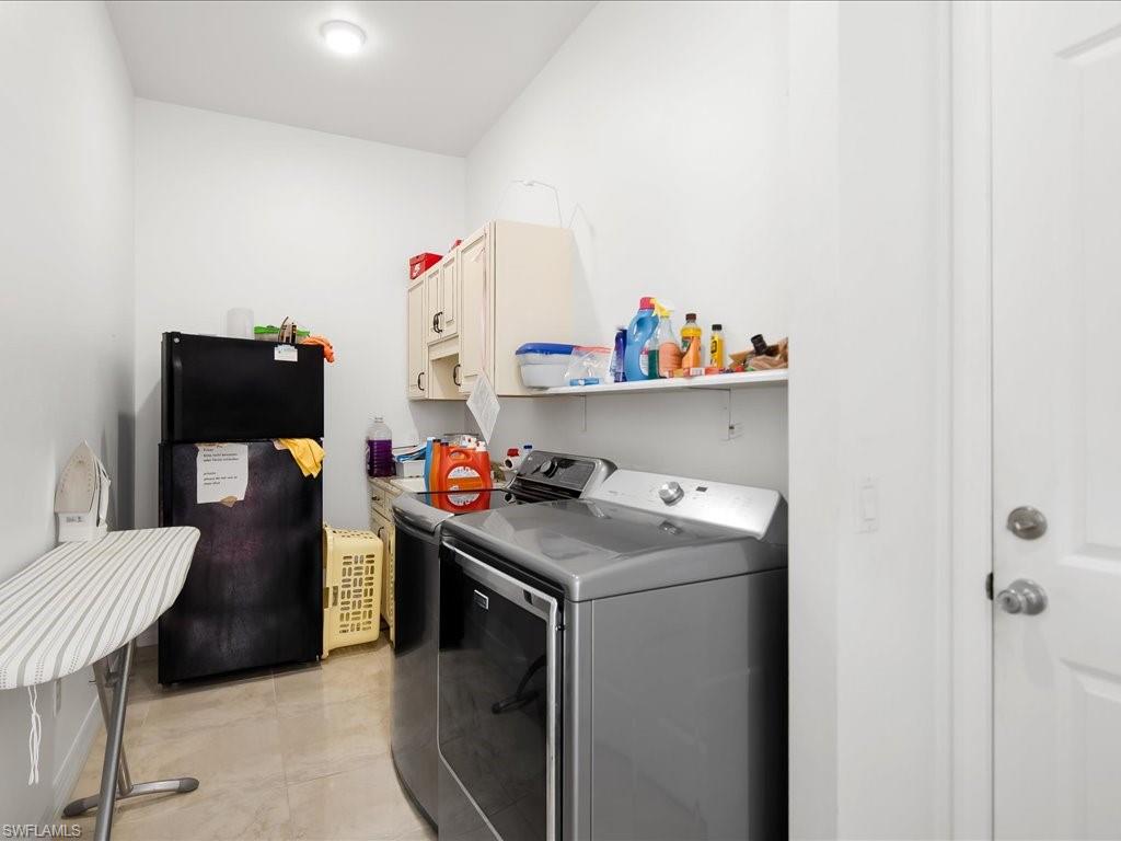 Laundry room with cabinet space, washing machine and clothes dryer, and light tile patterned floors