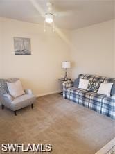 Carpeted living area featuring a ceiling fan