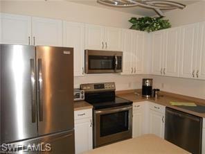 Kitchen with stainless steel appliances, white cabinetry, and light countertops