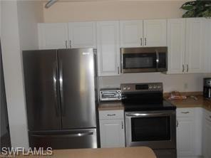 Kitchen featuring appliances with stainless steel finishes and white cabinets