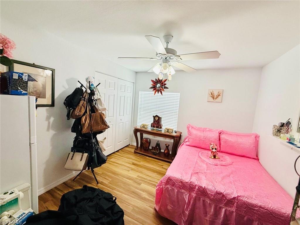 Bedroom featuring freestanding refrigerator, wood finished floors, ceiling fan, and a closet