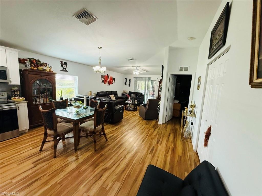 Dining space featuring healthy amount of natural light, light wood-type flooring, a ceiling fan, and a chandelier