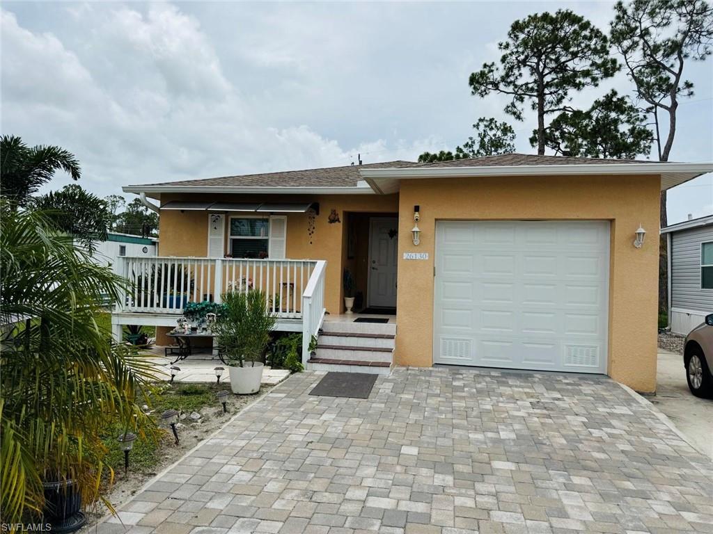 View of front of home with stucco siding, a garage, decorative driveway, and covered porch