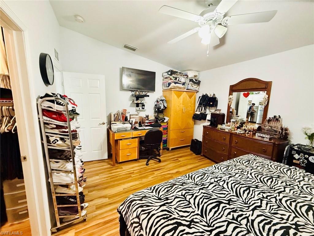 Bedroom featuring light wood-style floors, vaulted ceiling, a ceiling fan, and a desk