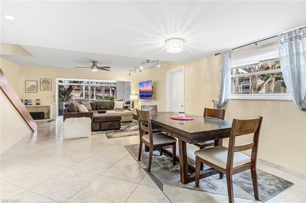 Dining room with a ceiling fan, light marble finish floors, and rail lighting
