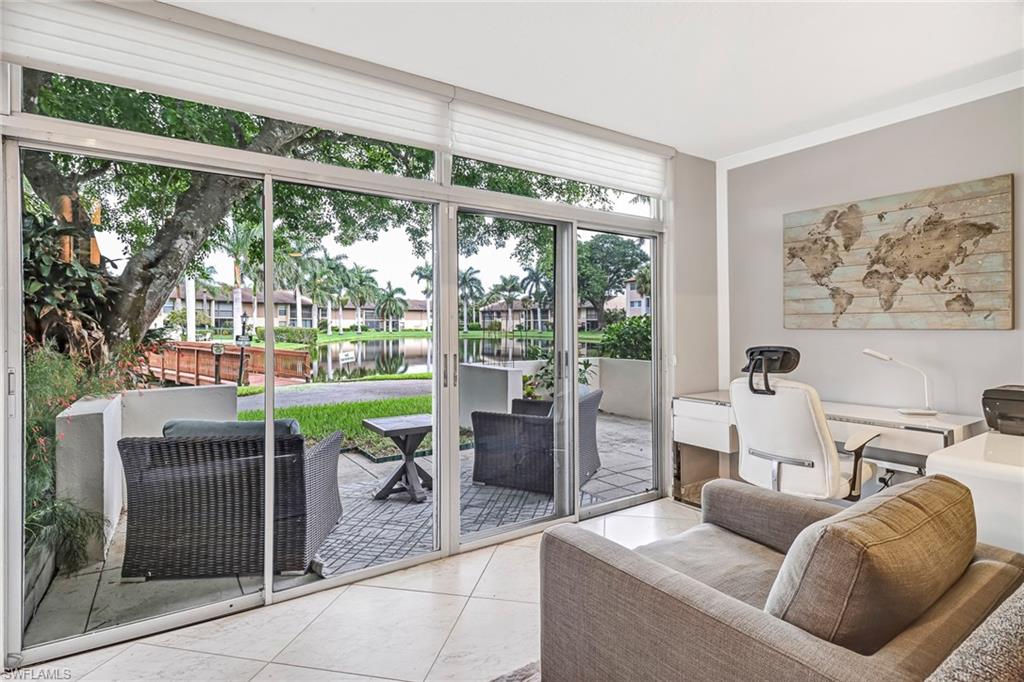 Living room featuring a water view, expansive windows, tile patterned flooring, and a desk