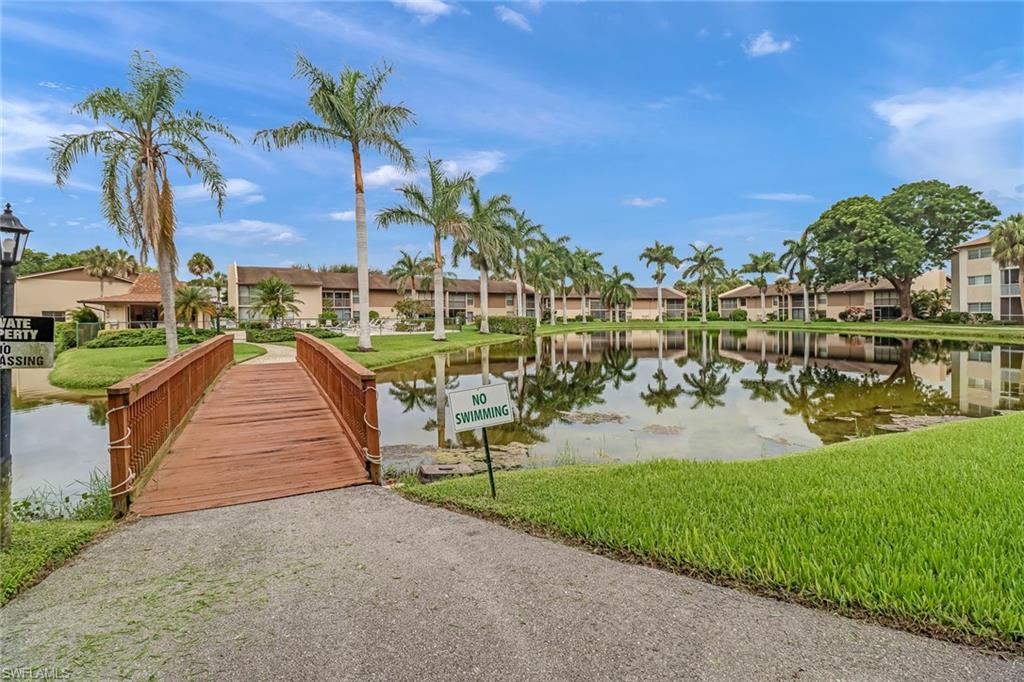 Dock featuring a water view, a lawn, and a residential view
