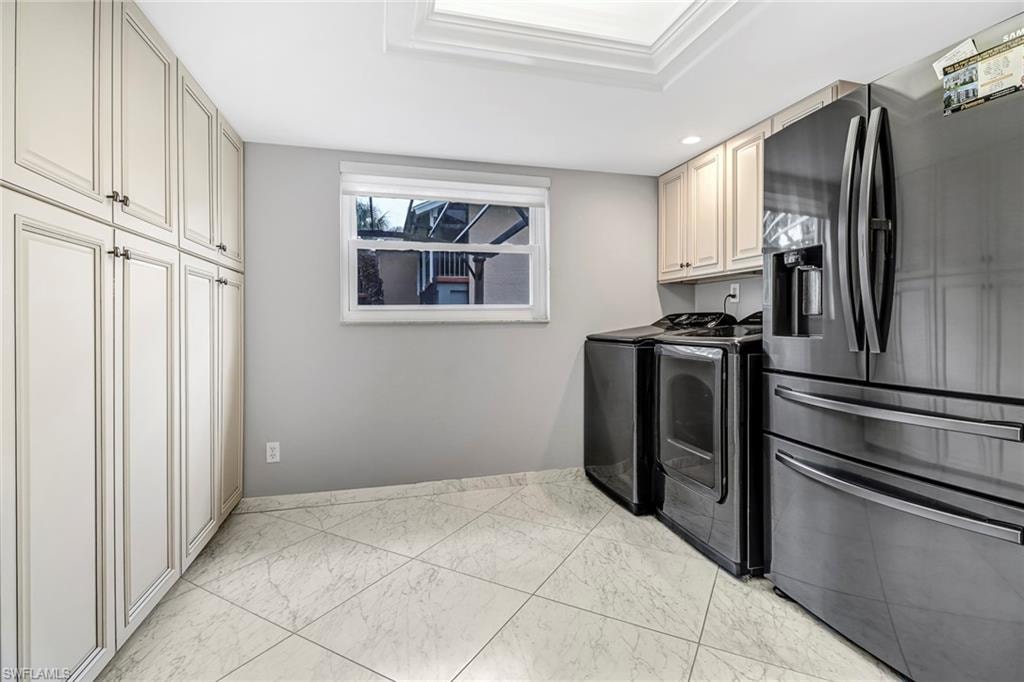 Washroom featuring washer and clothes dryer and light marble finish floors