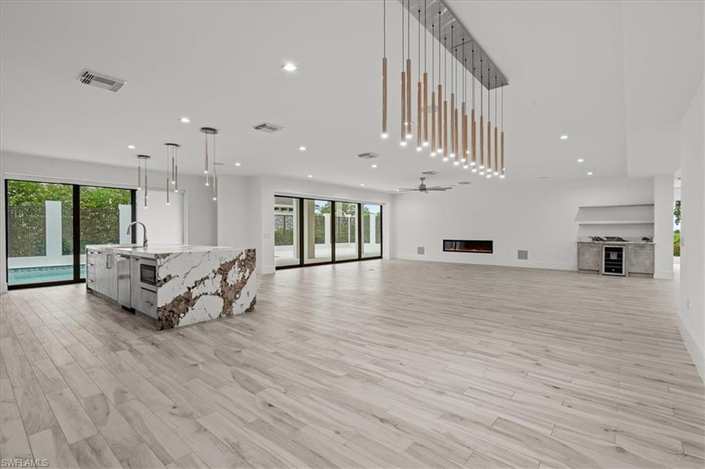 Living area with recessed lighting, a glass covered fireplace, light wood finished floors, wine cooler, and a ceiling fan