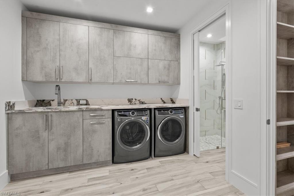 Laundry room featuring washing machine and dryer, cabinet space, light wood-style flooring, and recessed lighting