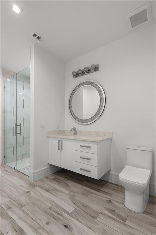 Bathroom featuring vanity, a marble finish shower, and wood tiled floors