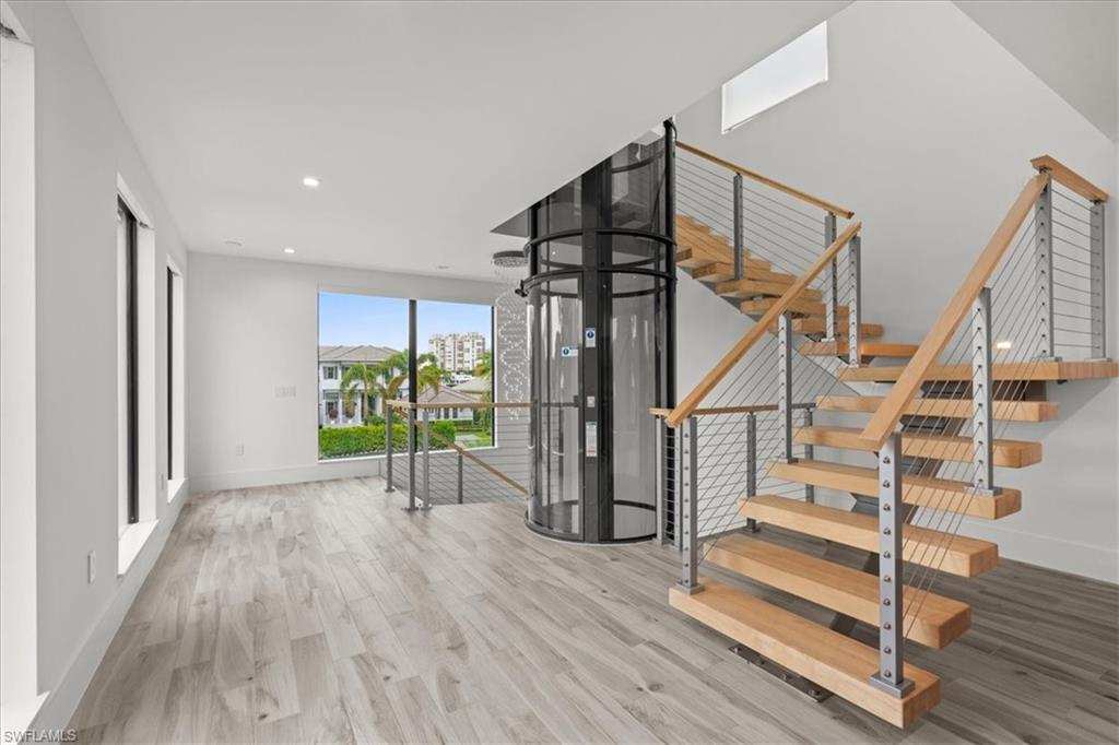 Stairs with wood finished floors and recessed lighting